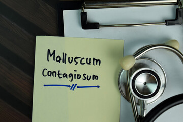 Molluscum Contagiosum write on a paperwork isolated on Wooden Table.