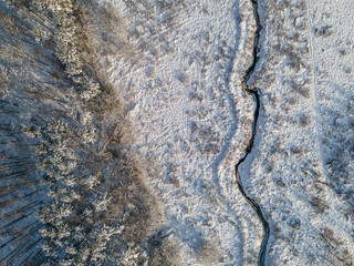 aerial view of snowy winter landscape with forest and meandering brook