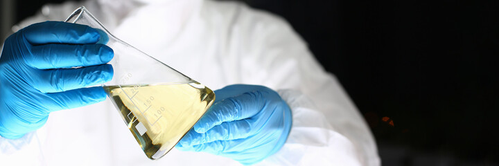 Cropped photo of male hands wearing protective blue gloves and holding flask in the laboratory