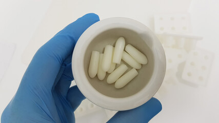 Closeup shot of a scientist's or researcher's hand holding suppositories in the pharmacy laboratory