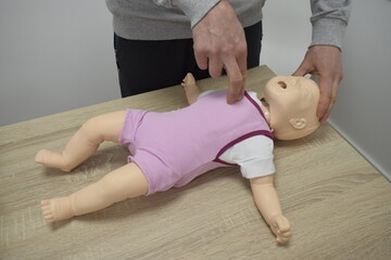 Sanitario mostrando cómo hacer primeros auxilios a un bebé con un maniquí. Reanimación cardiopulmonar. RCP