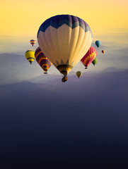 Hot Air Balloon flight over mountain valley in a dawn haze. Calm landscape with Hot-Air balloons at...