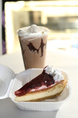 cherry cheesecake on a black background with reflection and flying icing sugar milkshake behind