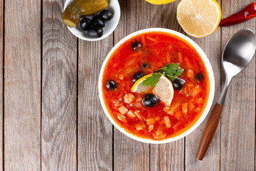 Solyanka, Russian soup with sausage, olives, pickled cucumber and capers. Top view with copy space