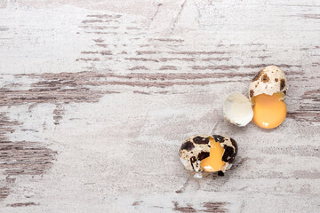 Two broken quail eggs on wooden table. Copy space