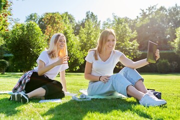 Two laughing talking female students using digital tablet for video communication