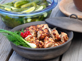 Grilled marinated chicken shashlik pieces in a bowl with greens