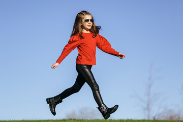 Caucasian girl with sunglasses, running in the park. Children concept