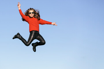 Fototapeta na wymiar Caucasian girl with sunglasses, jumping, flying, suspended in the air. In a sky backgrund. Children concept. Copyspace