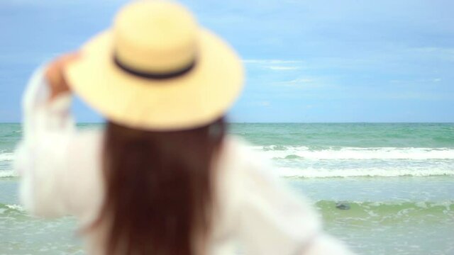 Close-up Of A Woman With Her Back To The Camera Walking Into The Frame Toward The Incoming Tide.