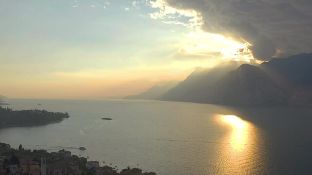 Amazing, aerial shot of Lake Garda at sunset with dramatic clouds and golden light in the background