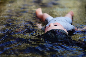 Corpse of a dead doll floating in water
