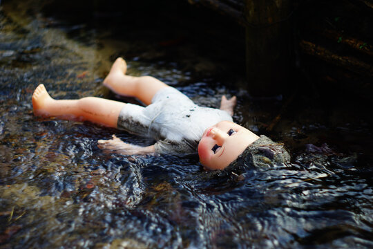 Corpse of a dead doll floating in water