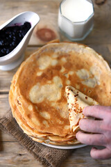 Soft focus. A stack of pancakes. A hand takes a pancake from a plate of pancakes. Pancake week.