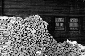 Black and white photo of firewood background and old wooden house with vintage windows