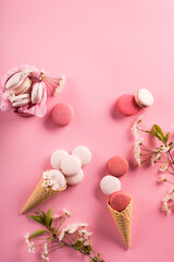 Rose macaroons in gift box and Cherry blossoms. Sweet macarons present on pink background. © Iuliia Metkalova