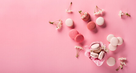 Rose macaroons in gift box and Cherry blossoms. Sweet macarons present on pink background.