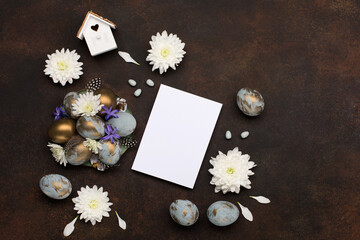 Obraz na płótnie Canvas Easter Decoration with gray blue golden eggs, quail feathers, white flowers on dark wooden background. Copy space, top view.