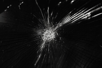Broken glass background with bullet hole over black background.