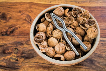 eine tonschale mit walnüssen und nussknacker