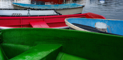 Fototapeta na wymiar Green, red, and blue weathered boats moored at the marina
