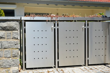 Gerätebox / Geräteschuppen oder Abfall-Kombination Sammelsystem und Geräteschuppen aus Edelstahl mit begrüntem Deckel vor einem Wohnhaus