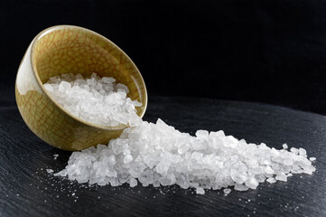 Sea salt in small porcelain bowl on black dish