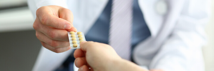 Cropped photo of medical worker giving pills for men after examination in clinic