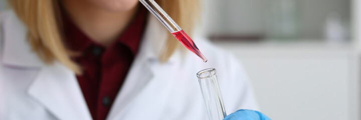 Young pretty woman wearing glasses and holding reagent tube while conducting research in the...