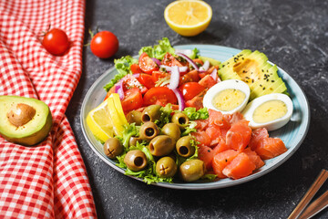Ketogenic, paleo diet lunch bowl with salted salmon fish, lemon, avocado, olives, boiled egg, tomato, green lettuce salad, healthy food