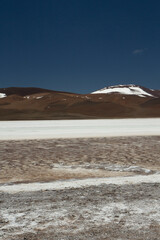 The white desert. Natural salt flats in the cordillera. View of the white salt field and brown mountains under a deep blue sky in Uyuni, Bolivia. 