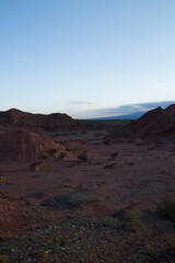 The red canyon and rocky valley at sunset. Panorama view of the arid desert, sandstone formations, and hills at nightfall. 