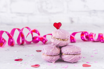 Homemade purple macarons, decorated with red, pink and white hearts for birthday, mother's or valentine's day, white background with copy space