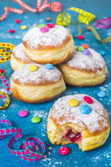 Krapfen, Berliner or donuts with streamers, confetti and chocolate beans. Colorful carnival or...