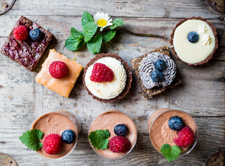 Selection of colorful and delicious cake desserts on wooden table.