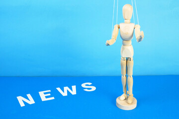 control a marionette by strings on fingers and word news on blue background