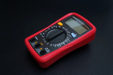 Red digital multimeter with on black table