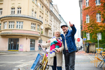 Fototapeta na wymiar Happy senior couple with bicycle outdoors on street in city.