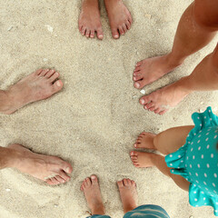 Family feet on the sand on the beach