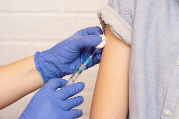 close-up of a hand in medical gloves with a syringe injection into the arm, vaccination theme