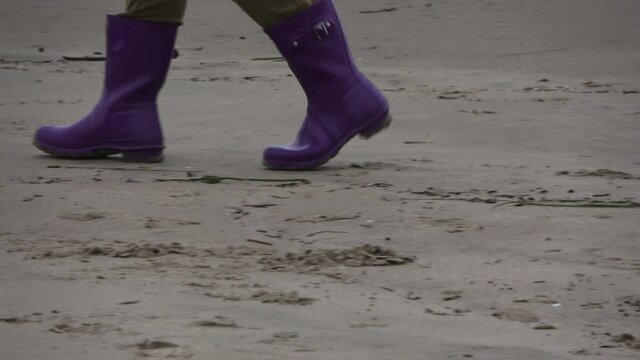 Purple boot walking on wet sand
