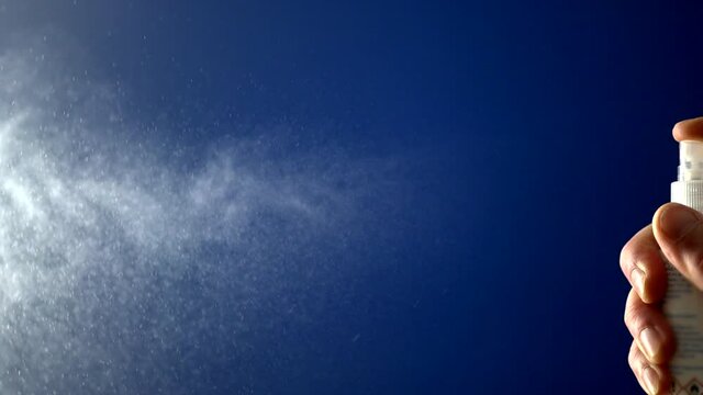 Spray from a spray bottle on a blue background slow motion
