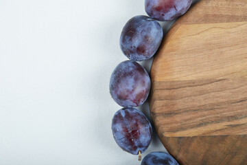 Group of fresh plums around the wooden plate