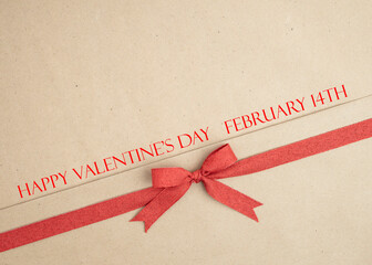 Brown kraft paper background for text, invitations, signs or holiday greetings with red fabric ribbon from above © TBergphoto