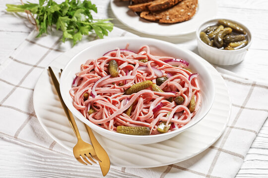 German sausage salad on a white plate, top view
