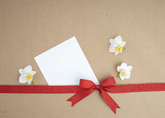 Brown kraft paper background for text, invitations, signs or holiday greetings with red fabric ribbon from above