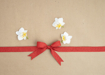 Brown kraft paper background for text, invitations, signs or holiday greetings with red fabric ribbon from above
