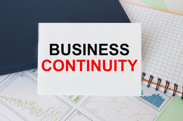 Business card with text Business Continuity laying on financial graphs