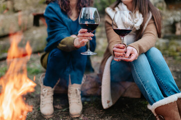 Close-up glass of red wine with unrecognizable women on background next to bonfire
