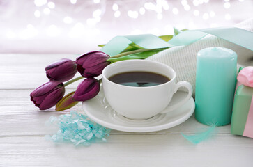 March 8, tulips, coffee and a cup of coffee on the background of a burning garland. Side view with copy space.